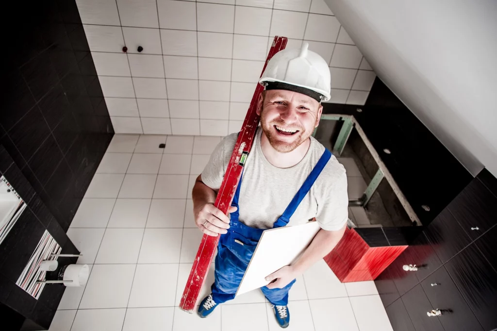 Homme blanc travaillant dans le bâtiment dans une salle avec des outils en train de sourire dans le recrutement.